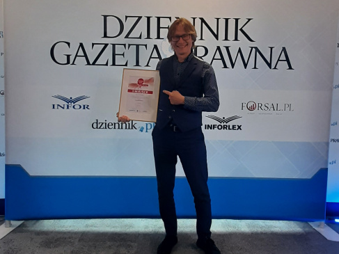 dr hab Marcin Pawłowski  z dyplomem na tle scianki.jpg