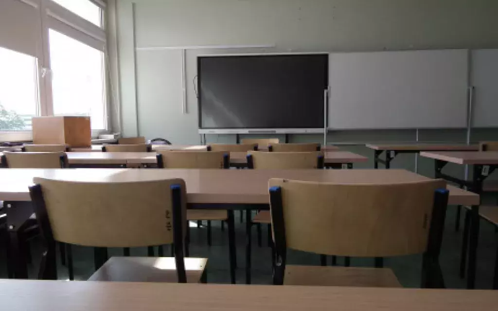 widok w stronę biurka prowadzącego w jednej z przykładowych sal dydaktycznych. W tle zielona tablica