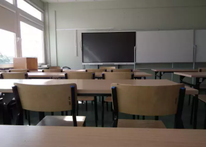 widok w stronę biurka prowadzącego w jednej z przykładowych sal dydaktycznych. W tle zielona tablica